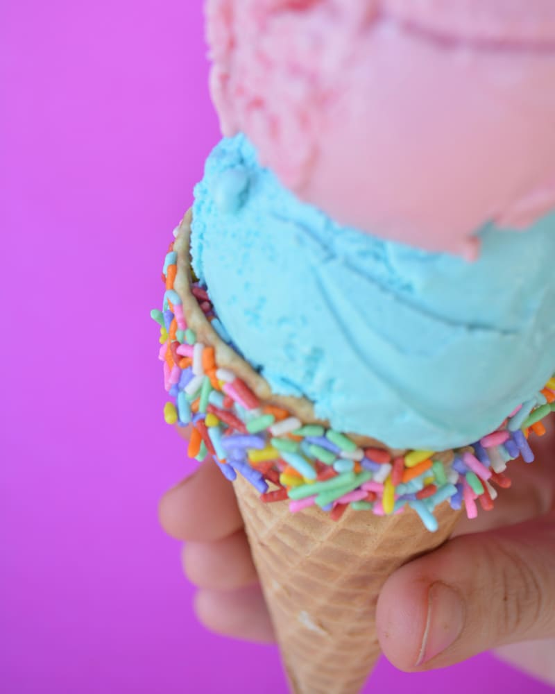 Een hoorntje met roze en blauw ijs en gekleurde spikkels