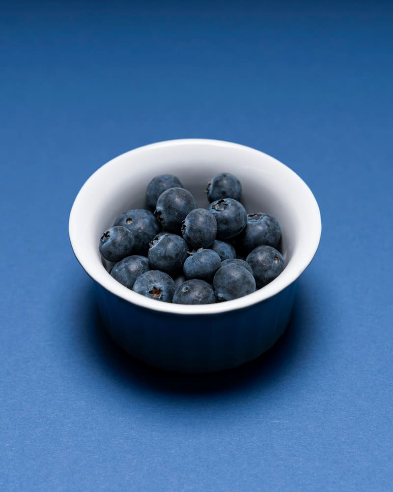 Een schaaltje blauwe bessen op een blauwe achtergrond