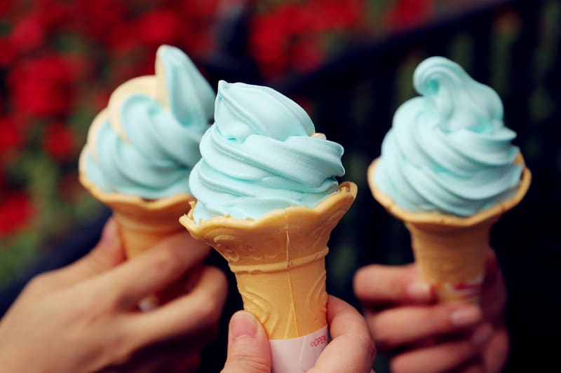 Drie handen tikken hoorntjes met blauw softijs tegen elkaar